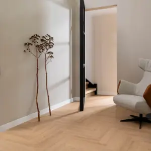 PVC vloer met warm eiken houtlook gelegd in visgraatmotief in een minimalistische woonkamer.